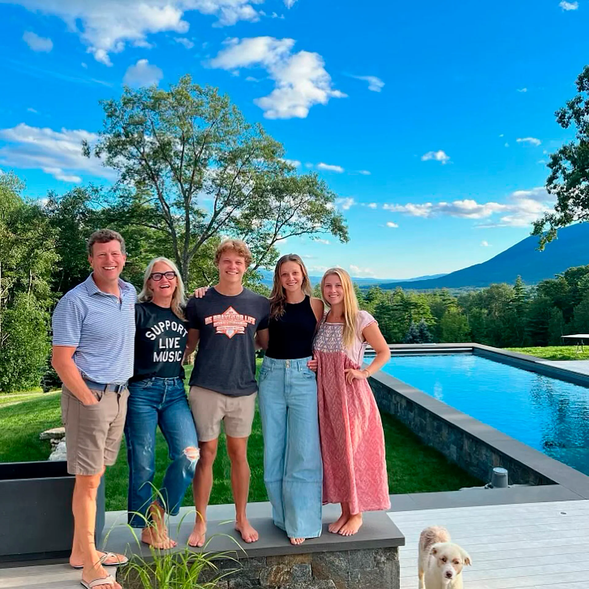 Chris, Mel, their three children and the family dog stand beside their backyard swimming pool. The background is a rural landscape.