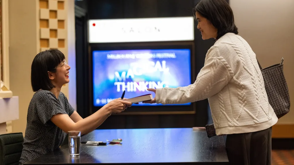 a woman handing a book to another woman to be signed at Melbourne Writers Festival