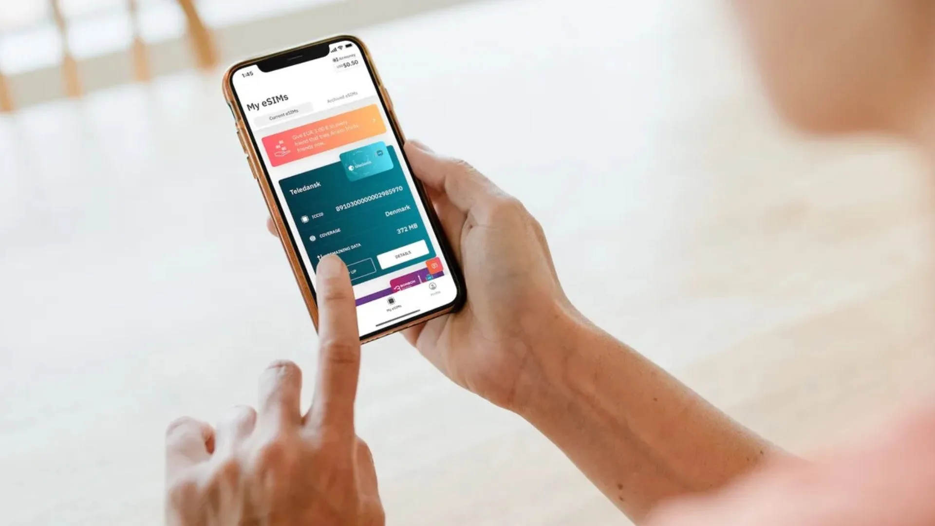 Close-up of a person's hands holding a smartphone and navigating the Airalo app interface, showing an active "Teledansk" eSIM plan for Denmark.