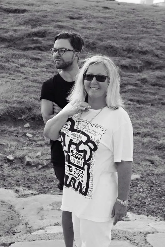 A black and white image of Rupert and Mandy outdoors. She is smiling and has a blonde bob.