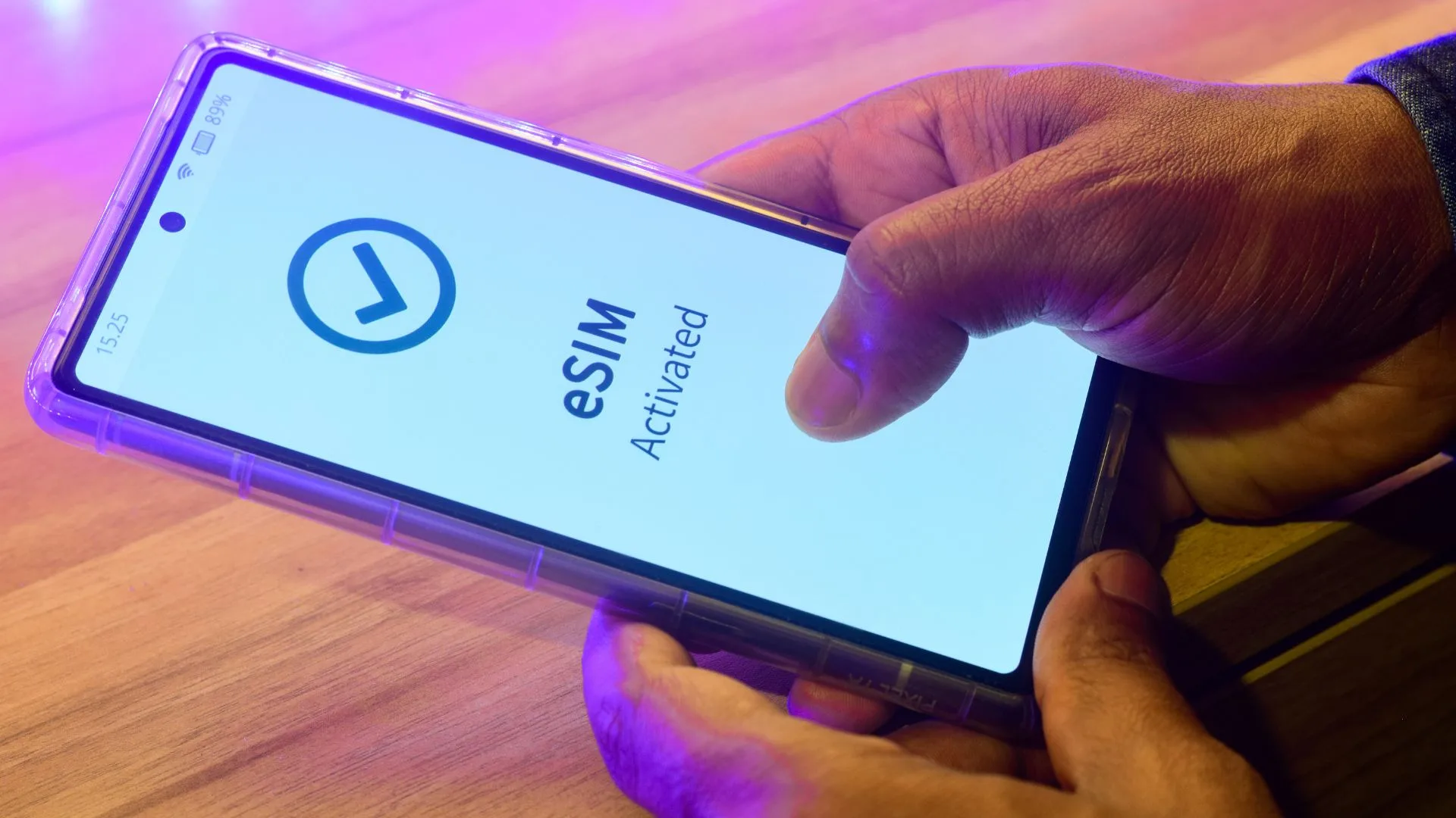 Close-up of a person holding a smartphone that displays a confirmation screen reading "eSIM Activated" with a large blue checkmark icon.