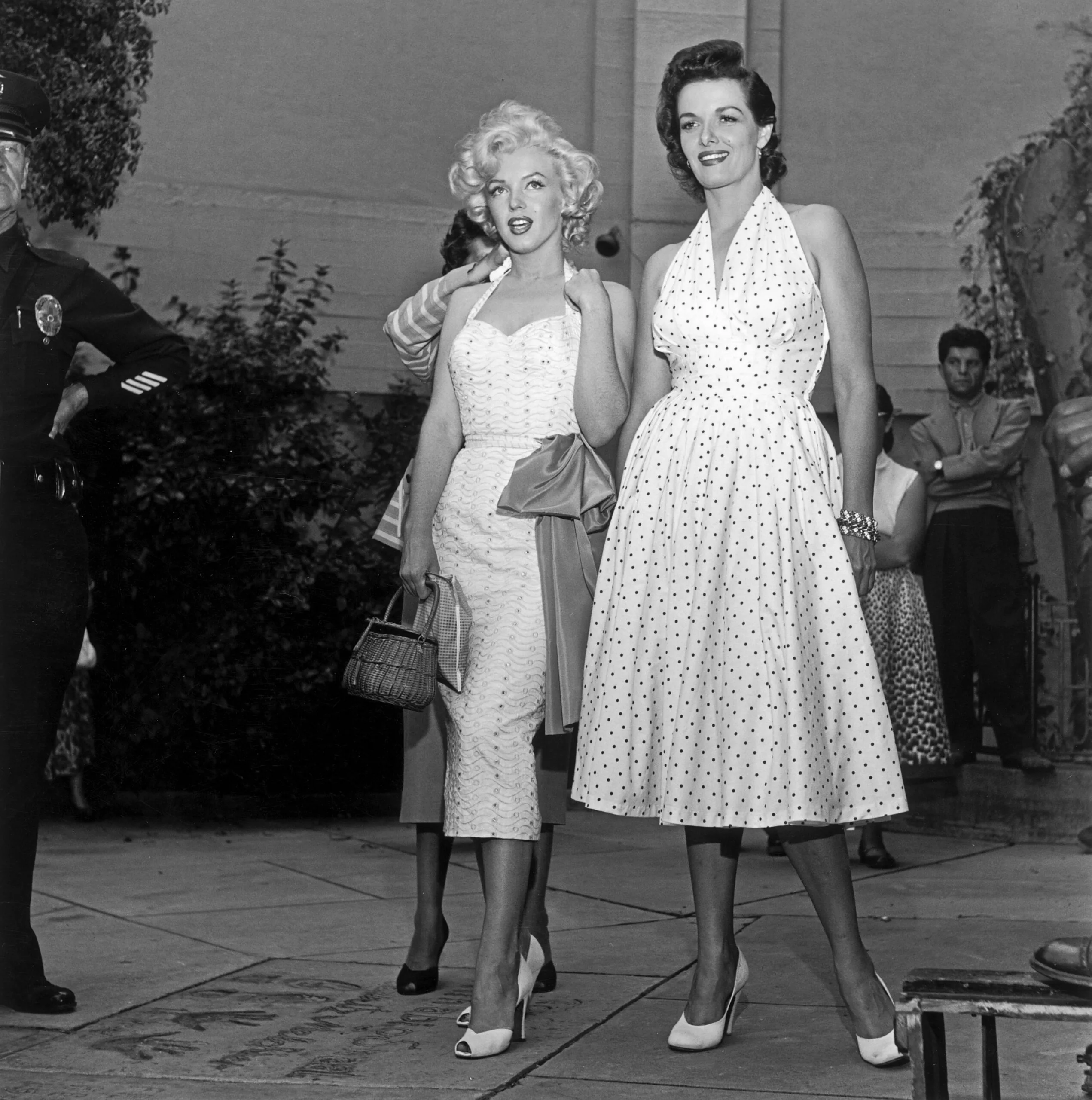 EXCLUSIVE American actresses Marilyn Monroe (1926 - 1962) (left) and Jane Russell stand in the courtyard of Grauman's Chinese Theater as they promote director Howard Hawks's film, 'Gentlemen Prefer Blondes,' Hollywood, California, June 26, 1953. A woman is adjusting Monroe's halter dress from behind. (Photo by M. Garrett/Murray Garrett/Getty Images)
