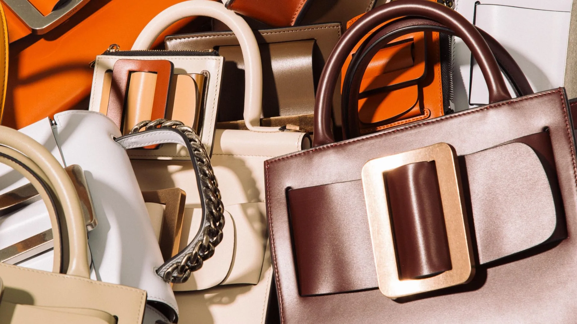 A collection of structured leather top-handle purses with oversized front buckles, illustrating a selection of the most durable designer bags.