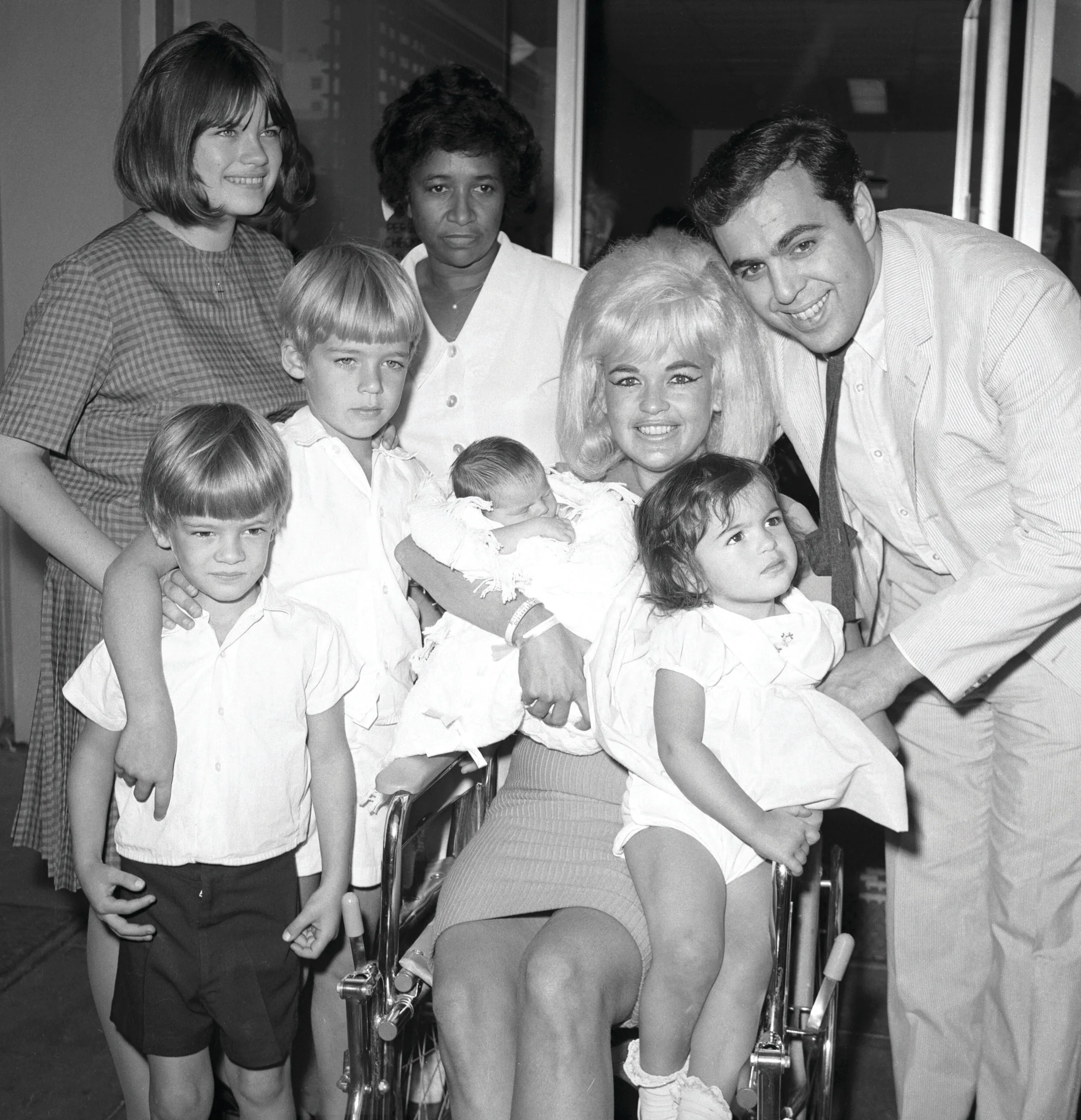 (Original Caption) Actress Jayne Mansfield and family are pictured here as the blonde actress leaves Cedars of Lebanon Hospital with the newest addition to the family, baby Anthony. Left to right are Jayne Marie Mansfield, 15, Zoltan Hargitay, 5, Mickey Hargitay Jr., 6, unidentified hospital attendant, Jayne holding baby Anthony, and husband Matt Cimber with Mariska Hargitay, 1. Anthony is the first child by Cimber.