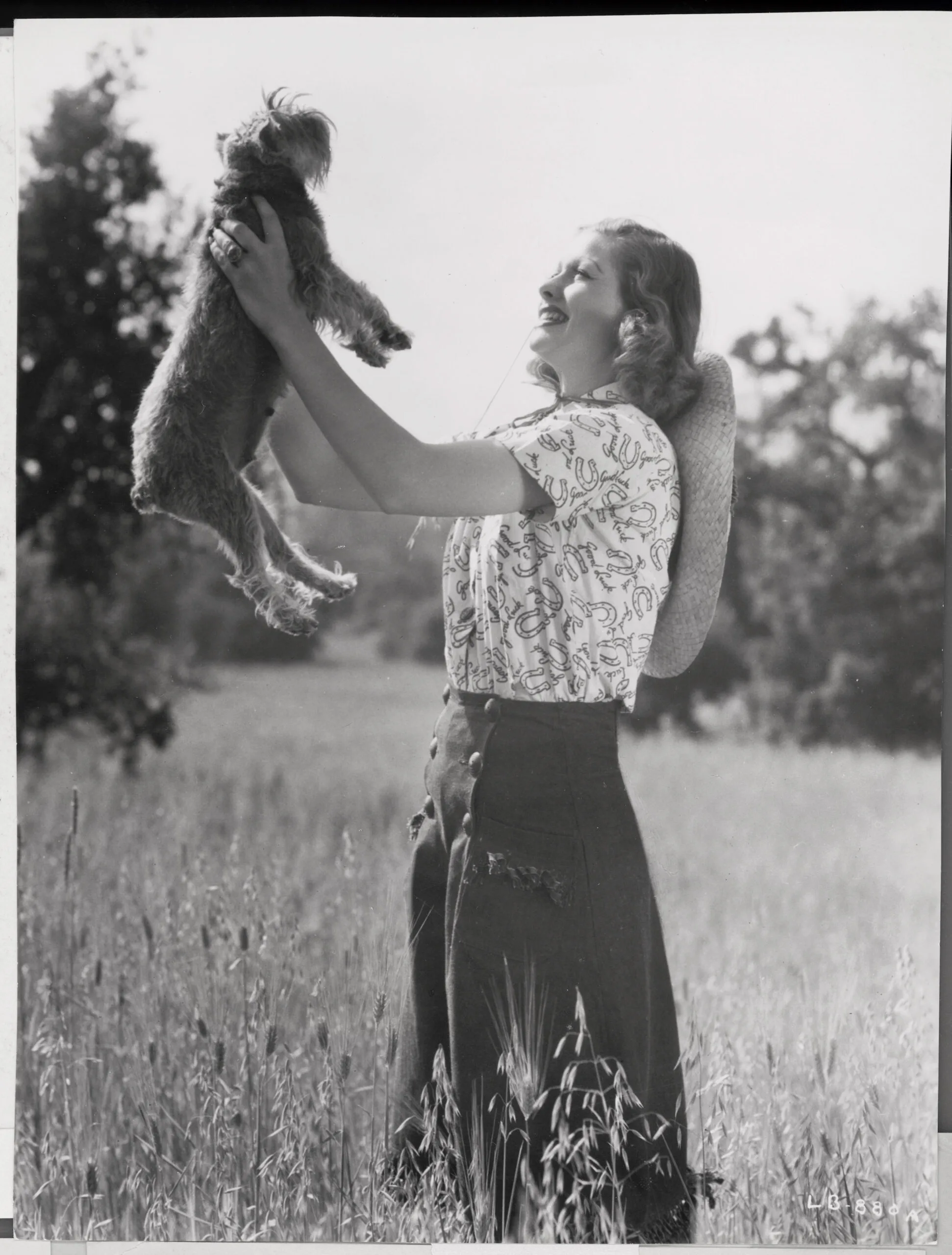 (Original Caption) Lucille Ball poses with pet dog in 1939 in a Good Luck pattern blouse, designed to get the picture of the then budding young RKO star in the papers. (Photo by George Rinhart/Corbis via Getty Images)