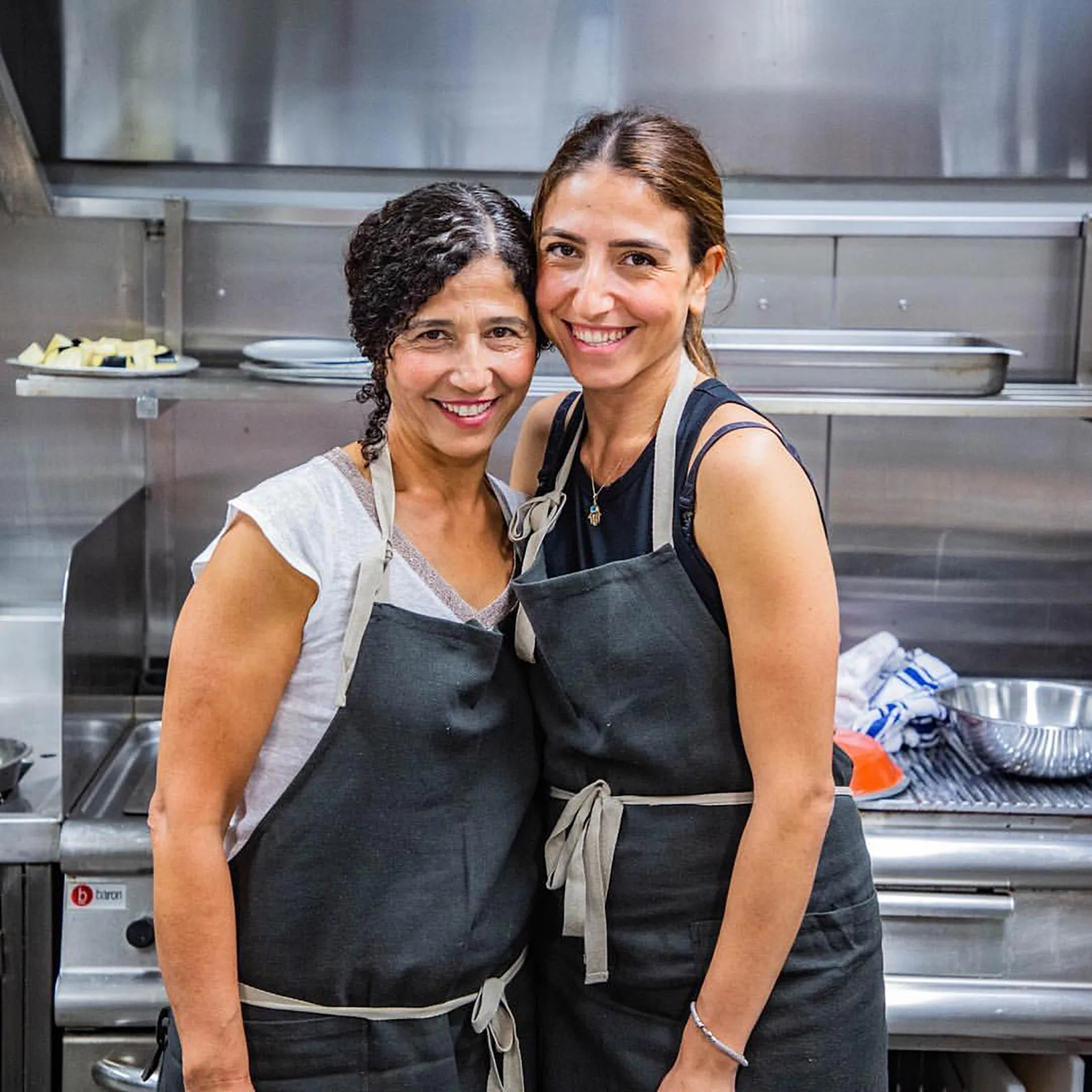 two women embrace in a kitchen.