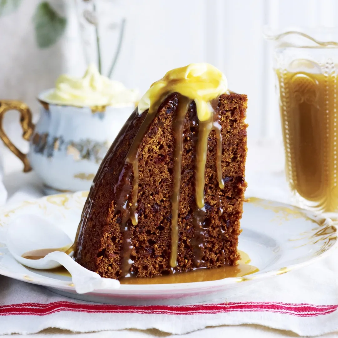 a slice of slow cooker sticky date pudding topped with sauce and butter