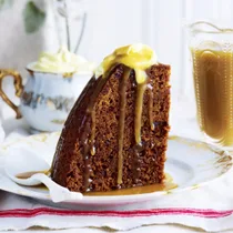 a slice of slow cooker sticky date pudding topped with sauce and butter