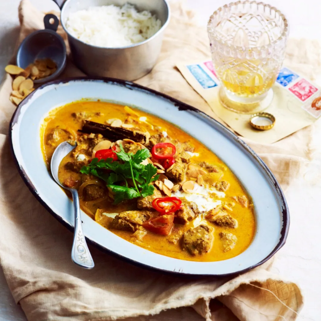 slow cooker lamb korma in an oval serving dish with a spoon
