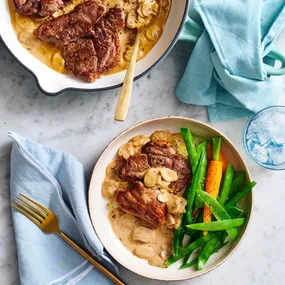 Lamb steaks with creamy mushroom sauce in a bowl with vegetables