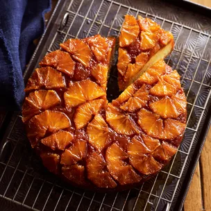 drippy orange syrup cake with a slice cut out on a metal rack