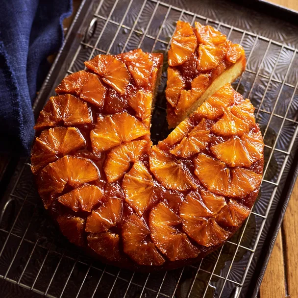 drippy orange syrup cake with a slice cut out on a metal rack