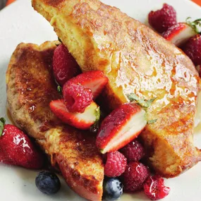 brioche bread french toast with berries, drizzled with maple syrup