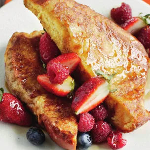 brioche bread french toast with berries, drizzled with maple syrup