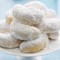 Kourabiedes (Greek almond biscuits) on a cake stand dusted with icing sugar
