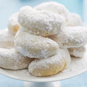 Kourabiedes (Greek almond biscuits) on a cake stand dusted with icing sugar
