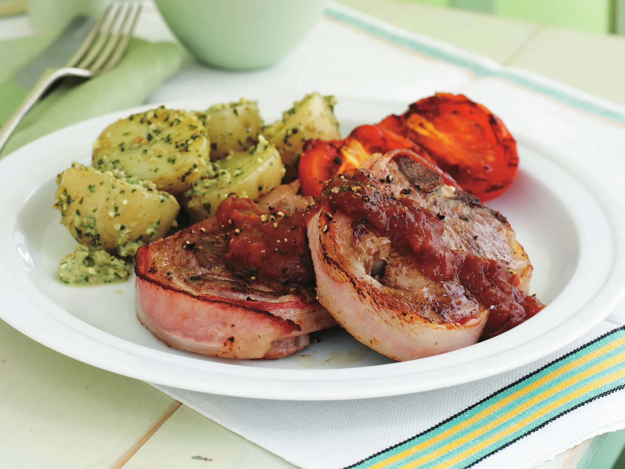 bacon-wrapped chops with baby potatoes in olive pesto