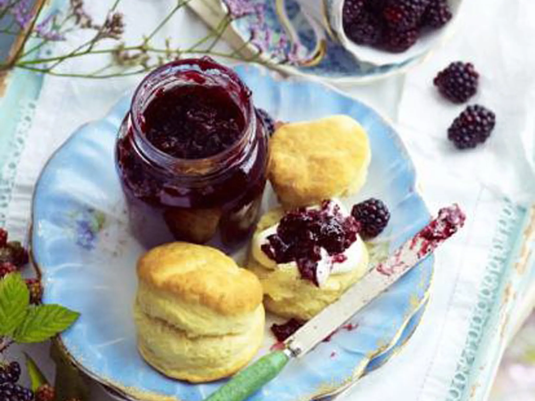 blackberry and pear jam in a jar on a plate with scones