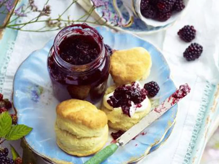 blackberry and pear jam in a jar on a plate with scones