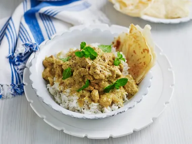 Chicken Korma Curry in a bowl with rice and roti