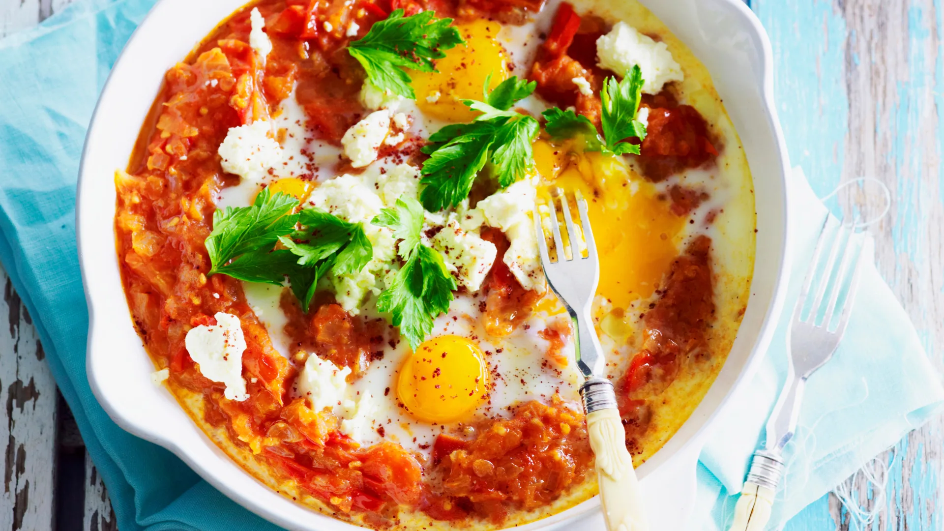 A skillet with shakshuka topped with fetta and parsley.
