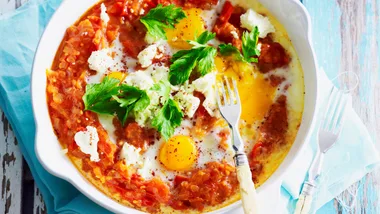 A skillet with shakshuka topped with fetta and parsley.