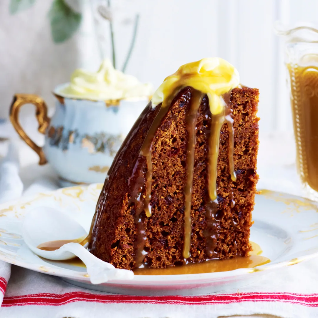 A slice of sticky date pudding made in a slow cooker with oozing caramel sauce