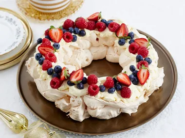 Pavlova wreath on a a plate decorated with berries