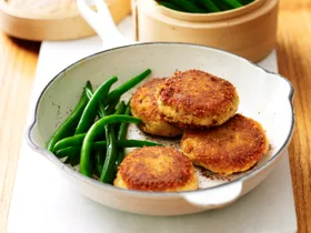 Salmon patties in a frying pan with green beans