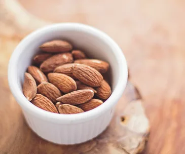 roasted and salted almonds in a white ramekin on a wooden table