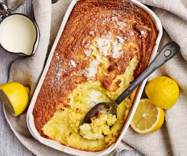 lemon delicious pudding in a white serving dish with a spoon