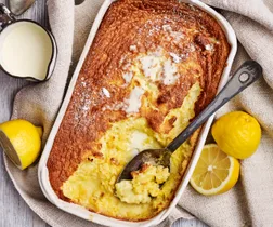 lemon delicious pudding in a white serving dish with a spoon