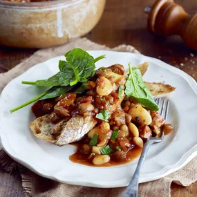 slow cooker boston baked beans on top of toast with spinach leaves