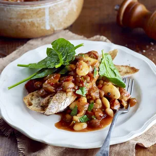 slow cooker boston baked beans on top of toast with spinach leaves