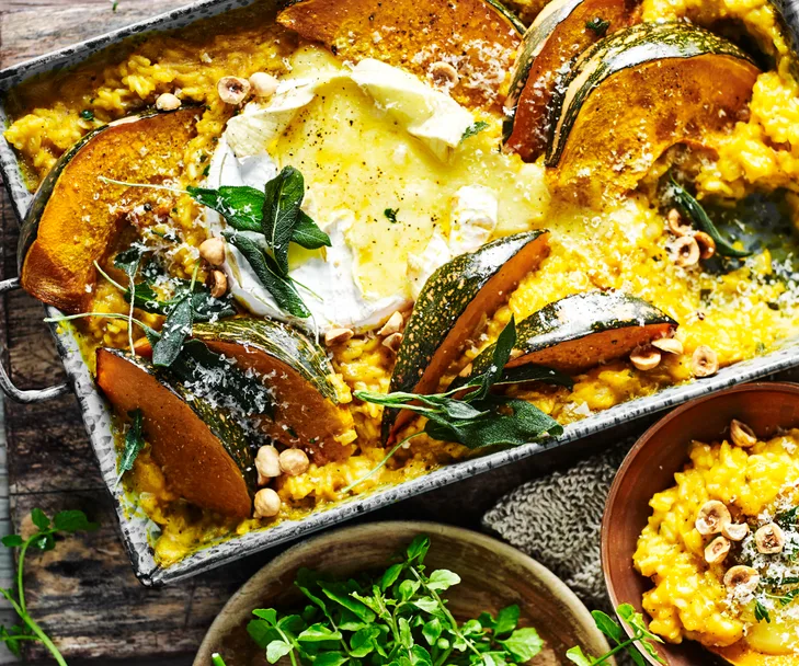 Tray of pumpkin risotto with a baked camembert in middle