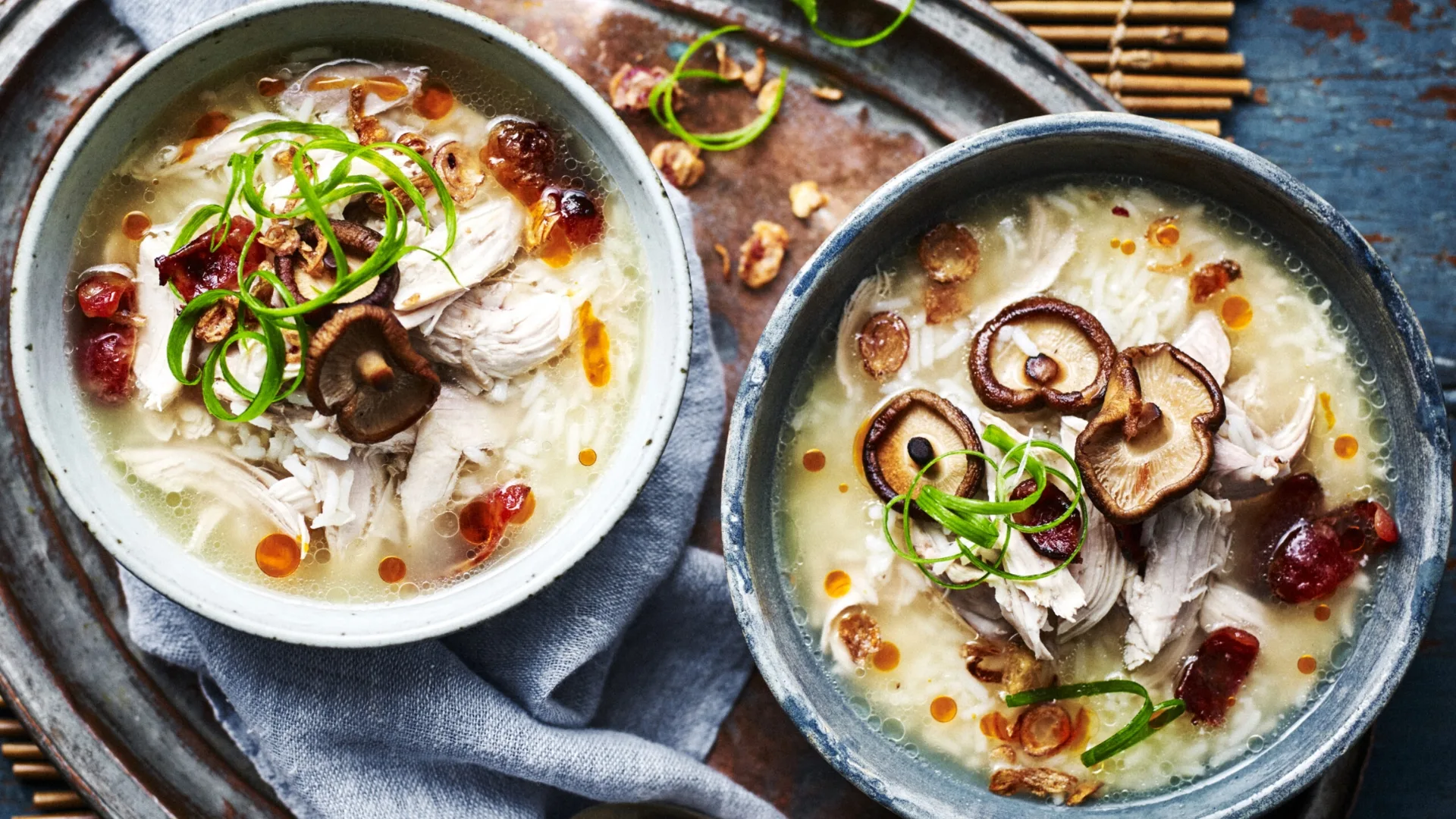 chicken congee in two bowls with mushroom, green onion and chilli oil