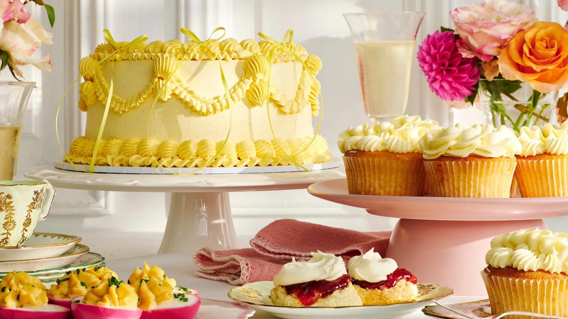high tea spread with cake, cupcakes, eggs and scones