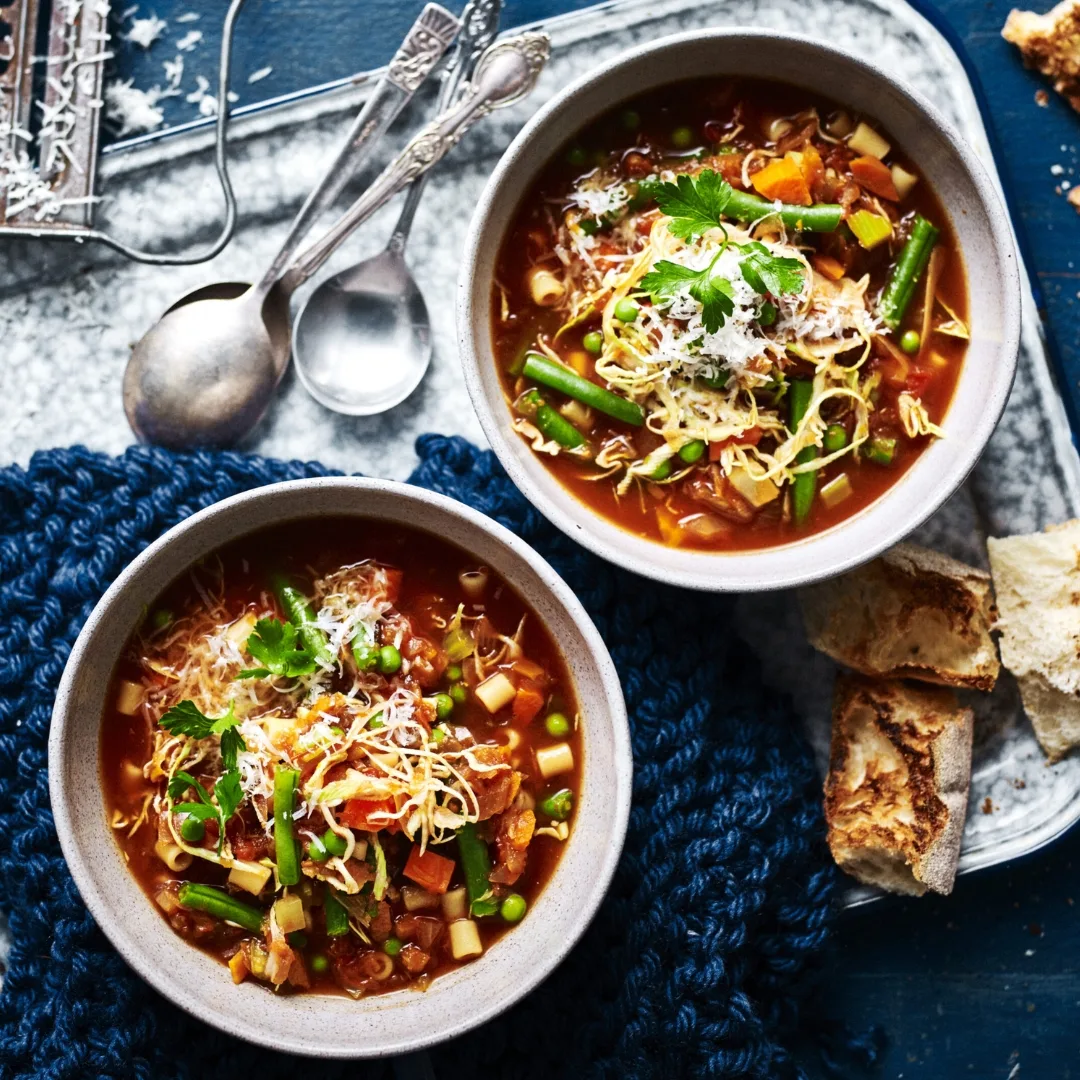 slow cooker vegetable minestrone in two bowls with spoons and bread