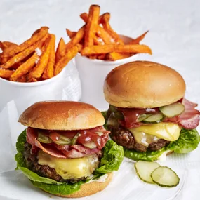 air fryer burger patties in two cheeseburgers with containers of sweet potato chips