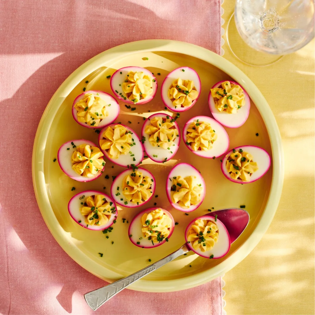 Pink devilled eggs on a yellow plate