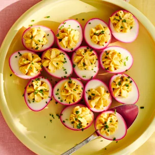 Pink devilled eggs on a yellow plate