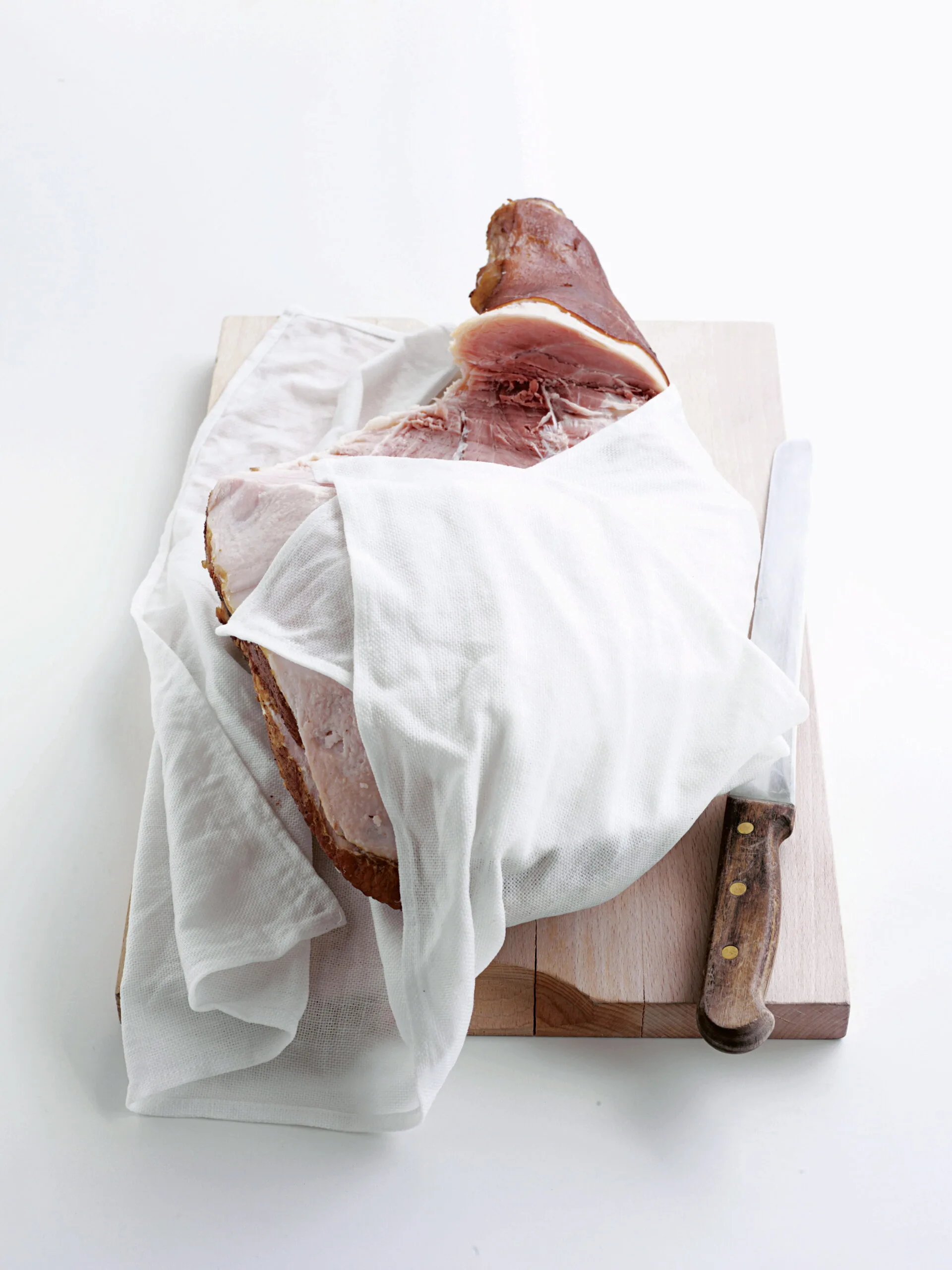 Wrapping cooked ham in a cloth or purpose-made ham bag seasoned with a vinegar solution will help keep it moist and fresh.