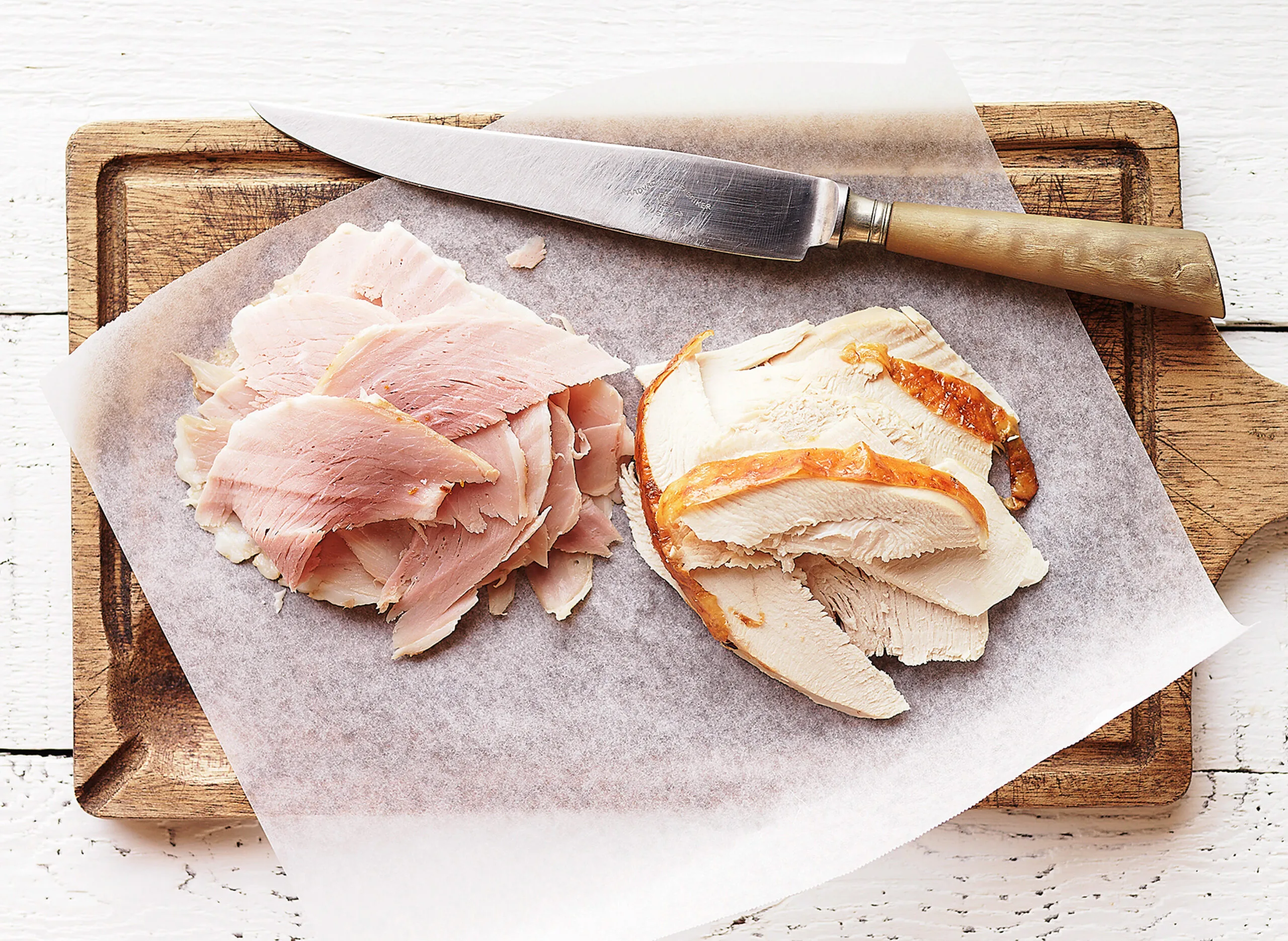 Ham and turkey slices on a chopping board.