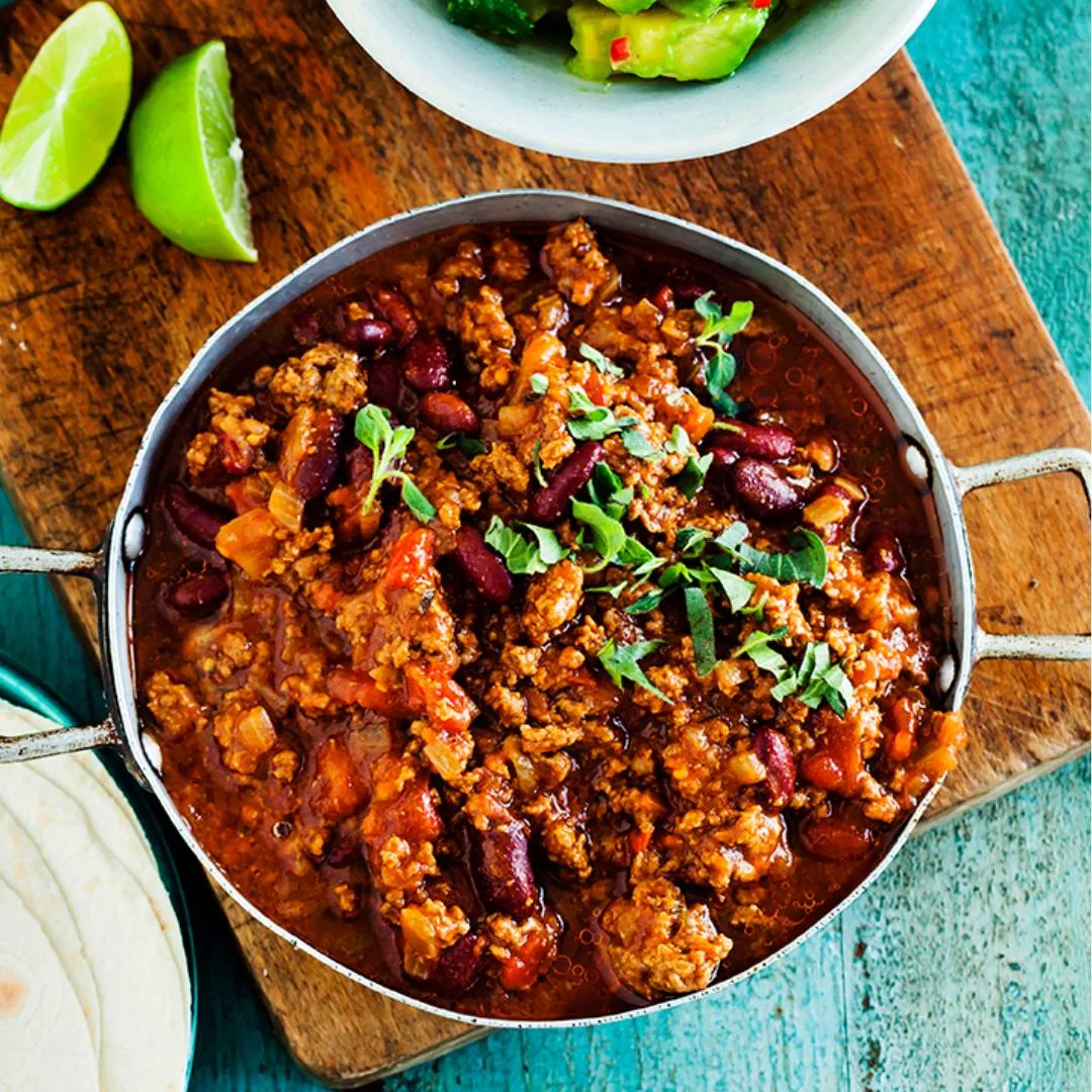 Chilli con carne with lime wedges and guacamole