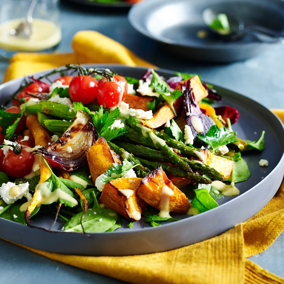 Roast vegetable salad on a plate with sweet potato, tomatoes and mixed greens