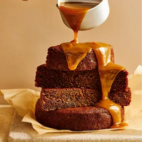 Sticky date pudding stacked up with thick caramel drizzling down