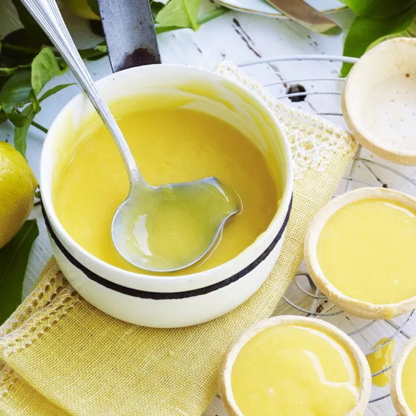 lemon curd recipe in a white saucepan with a ladle