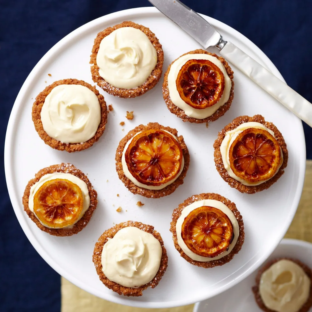 Mini no-bake lemon cheesecakes on a white stand, some with lemon slices on top