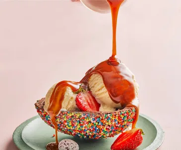 Scoops of ice-cream in half an Easter egg, with chocolate sauce poured over