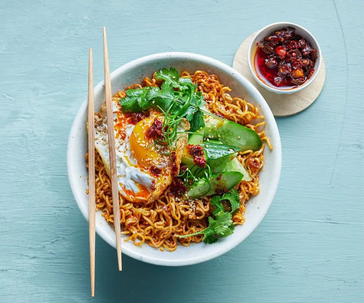 ramen noodles in a bowl, topped with greens and a fried egg